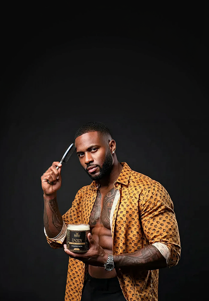 Man holding a jar and a brush against a black background